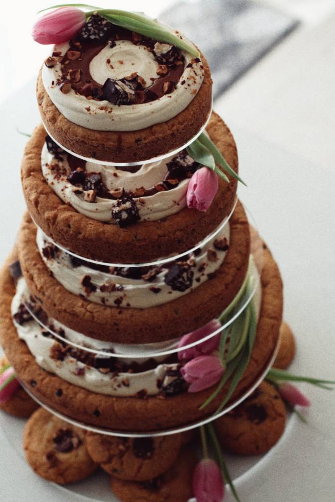 Gâteau fleuri vegan en étages décoré de fleurs fraîches pour mariage ou événement